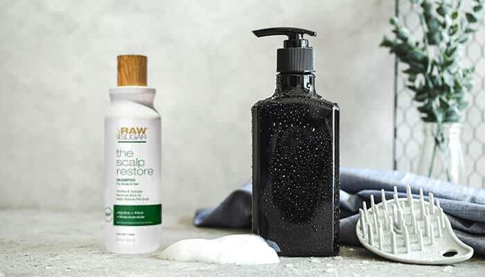 Do Raw Sugar Shampoo claimants receive any compensation - Startup Stride - Startup Stride Raw Sugar Shampoo products including The Scalp Restore Shampoo and a black bottle with a pump, alongside a hair brush, with a subtle foamy texture, relevant to the Raw Sugar Shampoo lawsuit.