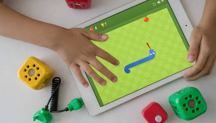 Knowing the Google Doodle Snake game - startup stride - Startup Stride Child playing a colorful snake game on a tablet surrounded by interactive toy blocks