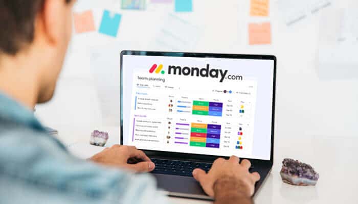What are the features offered by Monday com - Startup Stride - Startup Stride Professional using the monday.com login dashboard on a laptop to plan tasks, track projects, and manage team workflows efficiently.