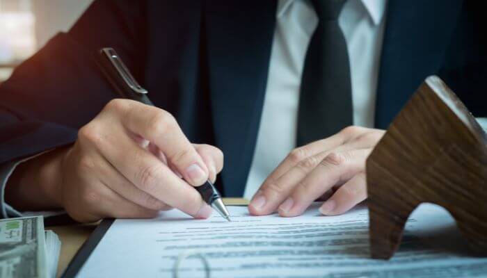 How to Get a Startup Business Loan With No Money Step-by-Step - Startup Stride Business owner signing paperwork while learning how to get a startup business loan with no money in 2026