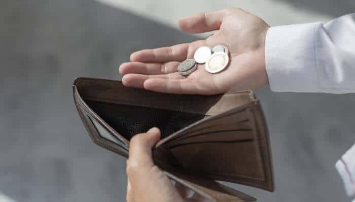 How to Start with No Money 1 - Startup Stride Person holding an empty wallet and coins while researching where do i start to become an entrepreneur with little money.